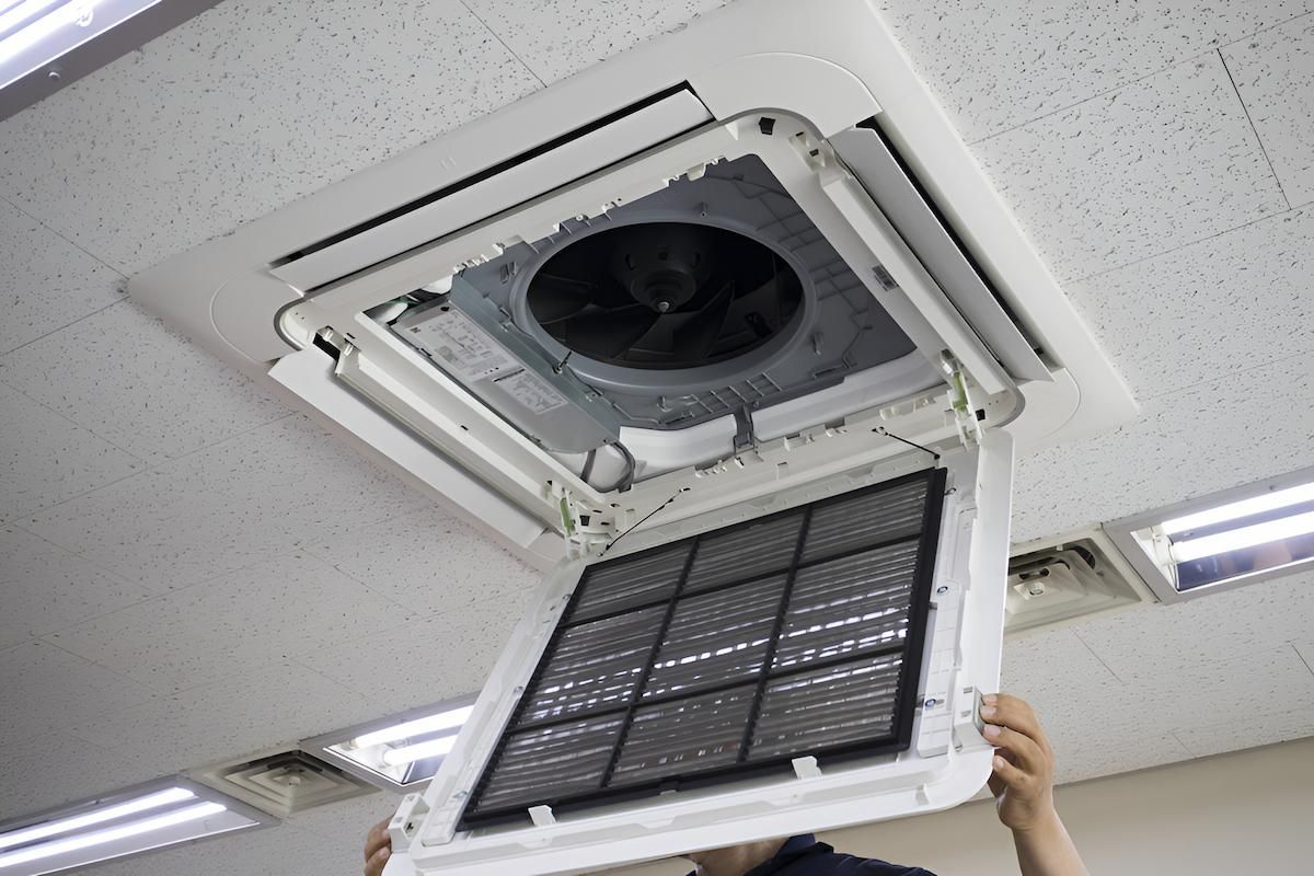 Ceiling-Mounted Air Conditioner With Open Filter Being Held by Hands — Refrigeration & Air Conditioning in Hunter Valley, NSW