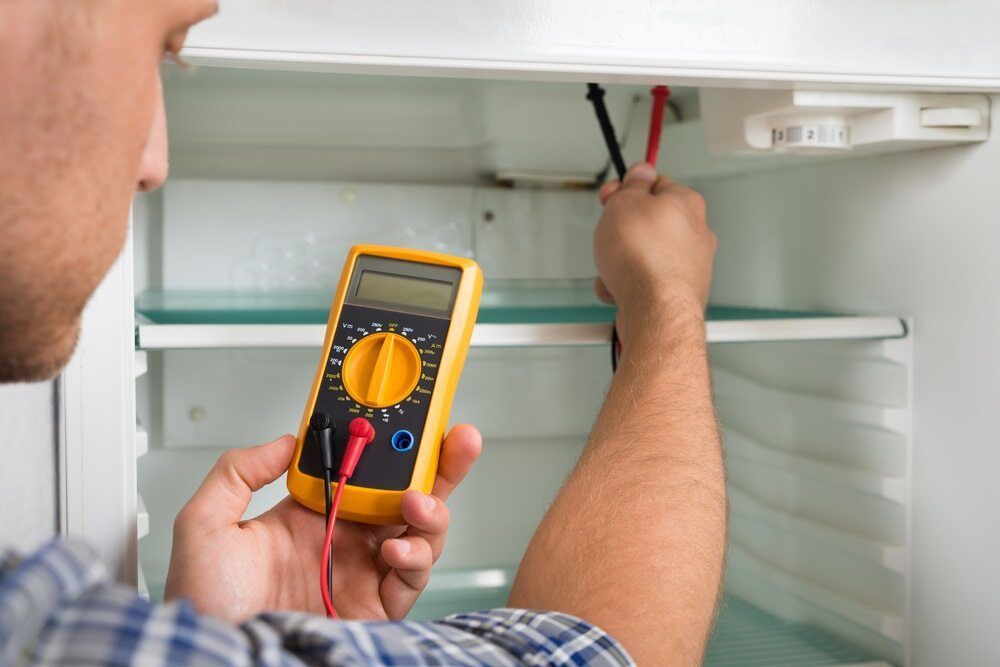 Man Using a Multimeter to Troubleshoot a Refrigerator — Refrigeration & Air Conditioning in Maitland, NSW