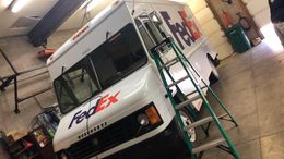 White FedEx truck with ladder inside a garage.