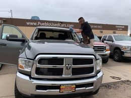Man replacing windshield on a gray Dodge Ram truck in front of 