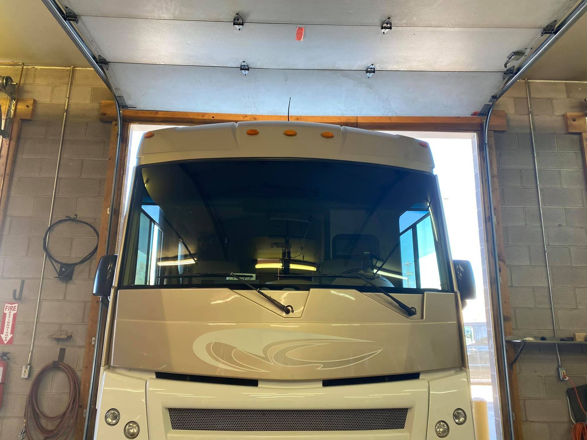 RV, tan and white, parked inside a garage, open door, natural light, front view.