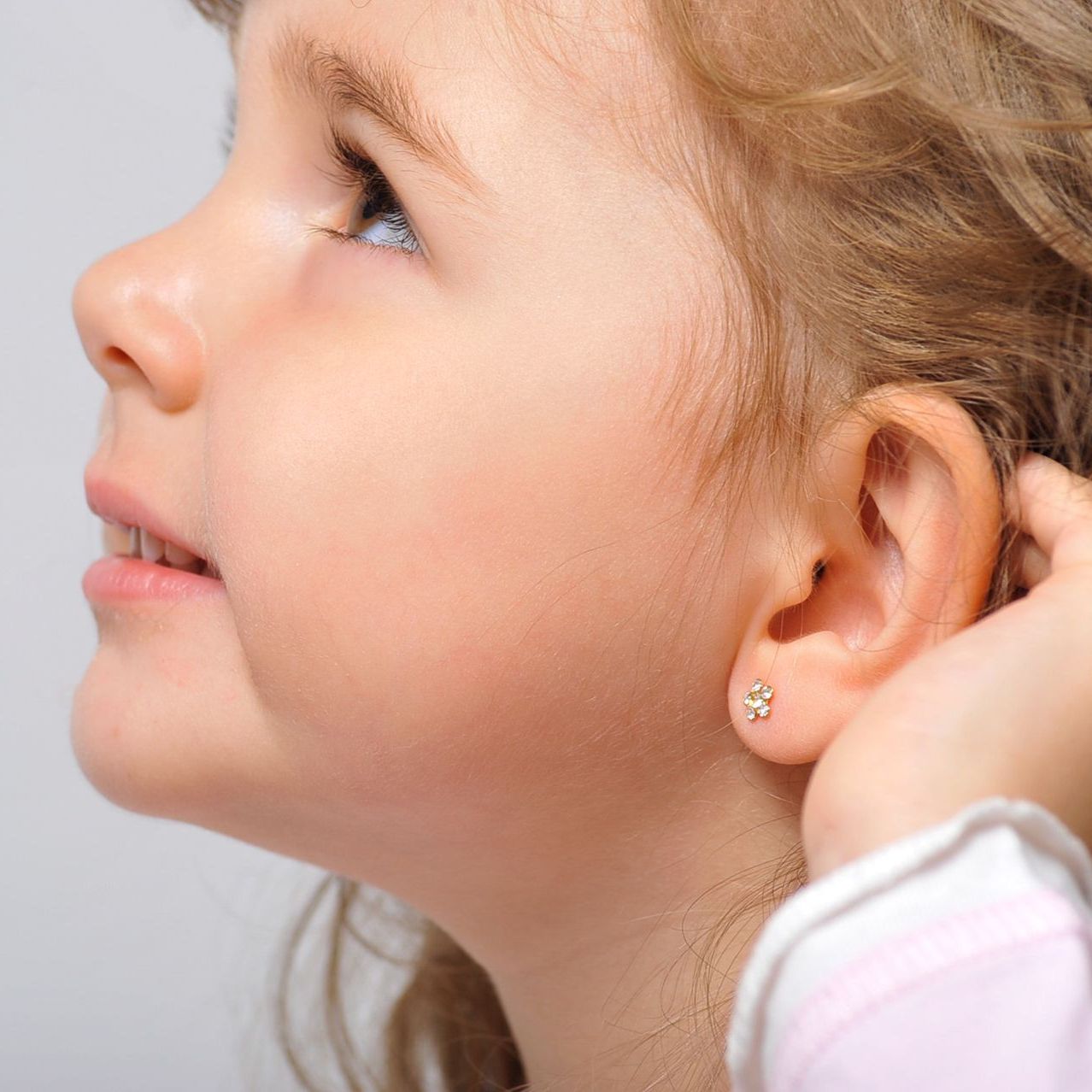 Ein kleines Mädchen trägt ein Paar Ohrringe .