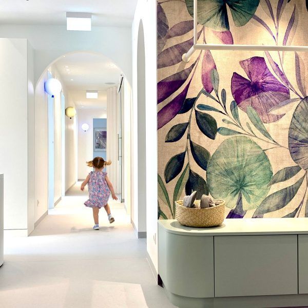 Ein kleines Mädchen läuft durch einen Flur mit einer Blumentapete an der Wand