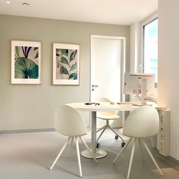 ein Raum mit einem Tisch und Stühlen und Bildern an den Wänden