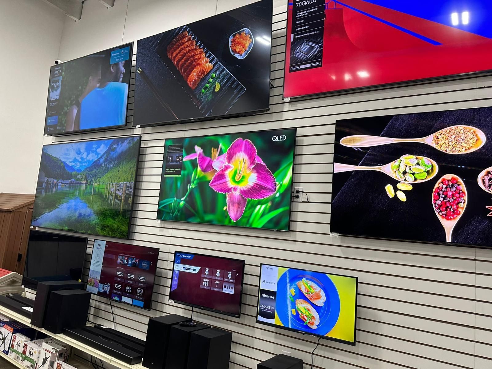 A bunch of televisions are hanging on a wall in a store.