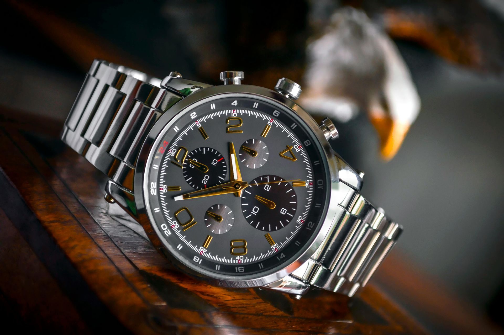 A silver watch is sitting on top of a wooden table.