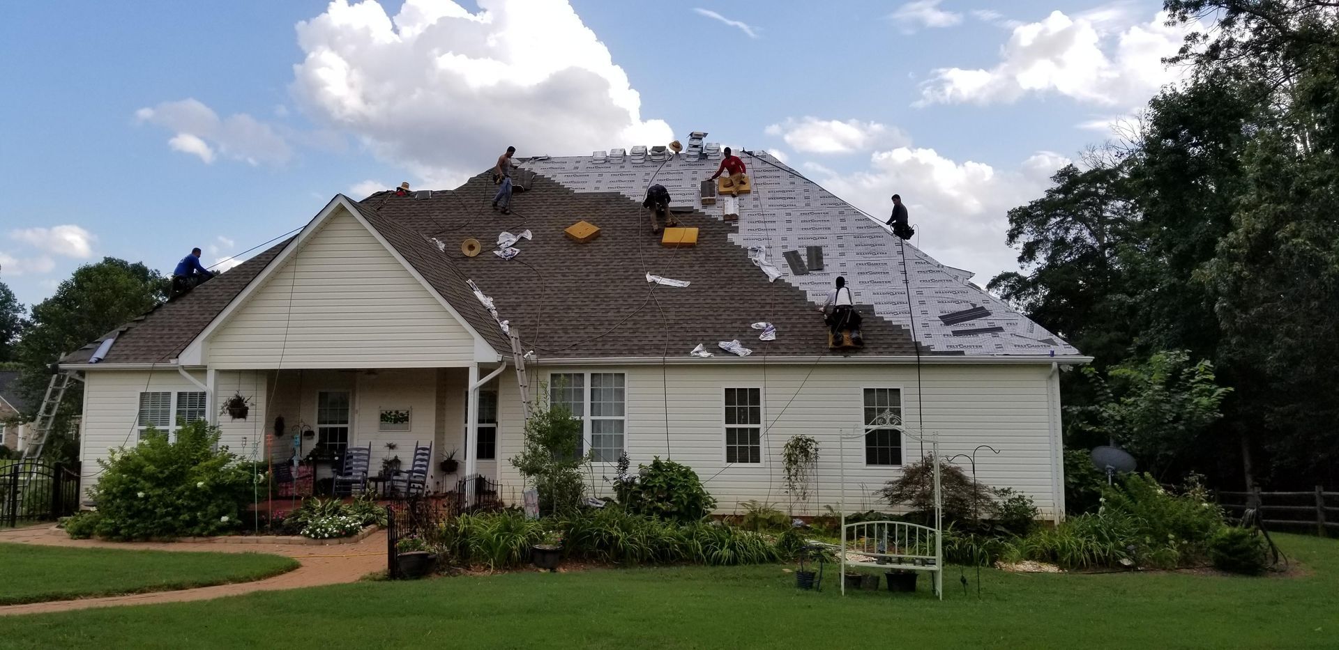 A white house with a roof that is being repaired