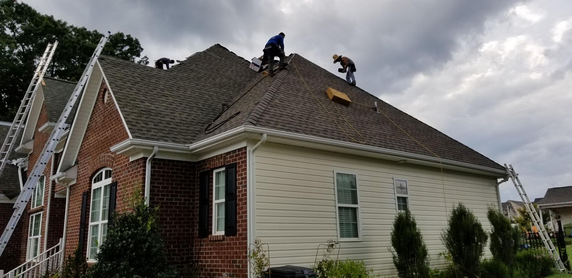A couple of men are working on the roof of a house.