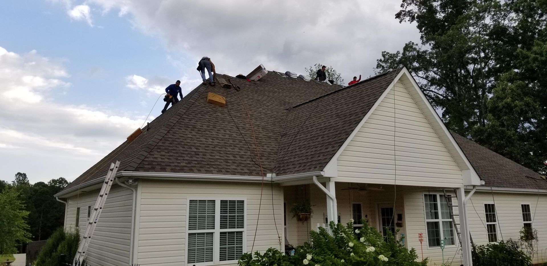 A group of people are working on the roof of a house.