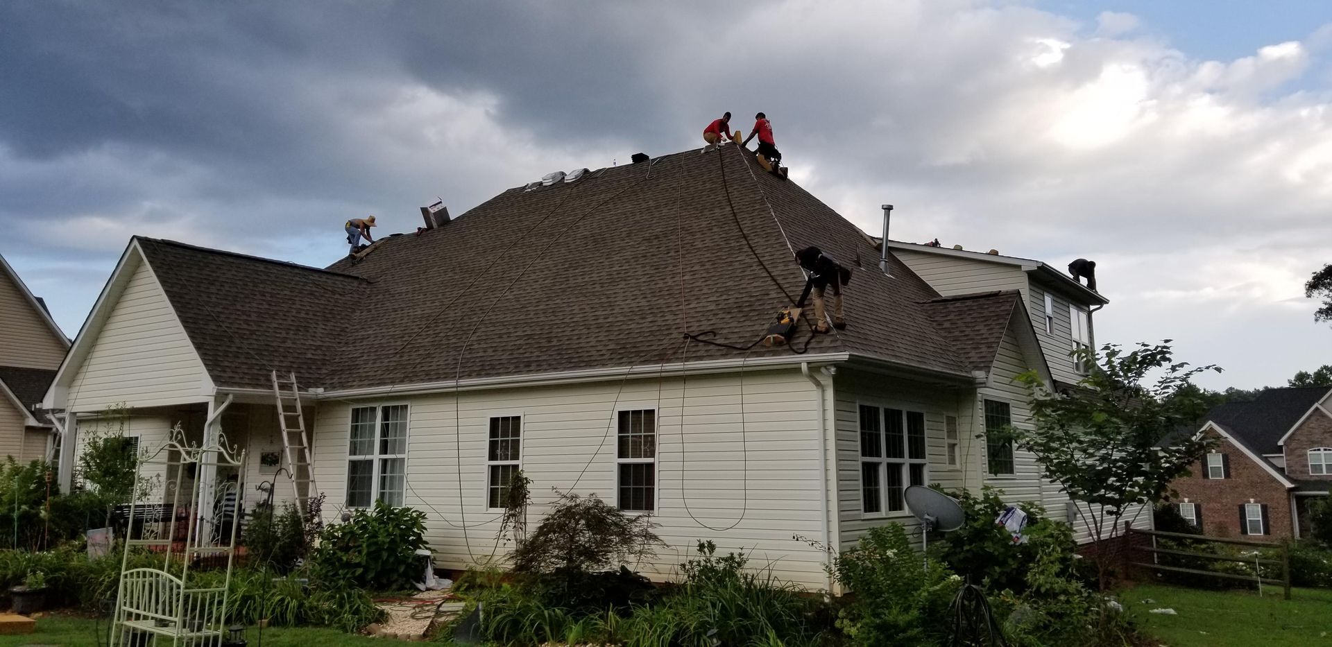 A group of people are working on the roof of a house.