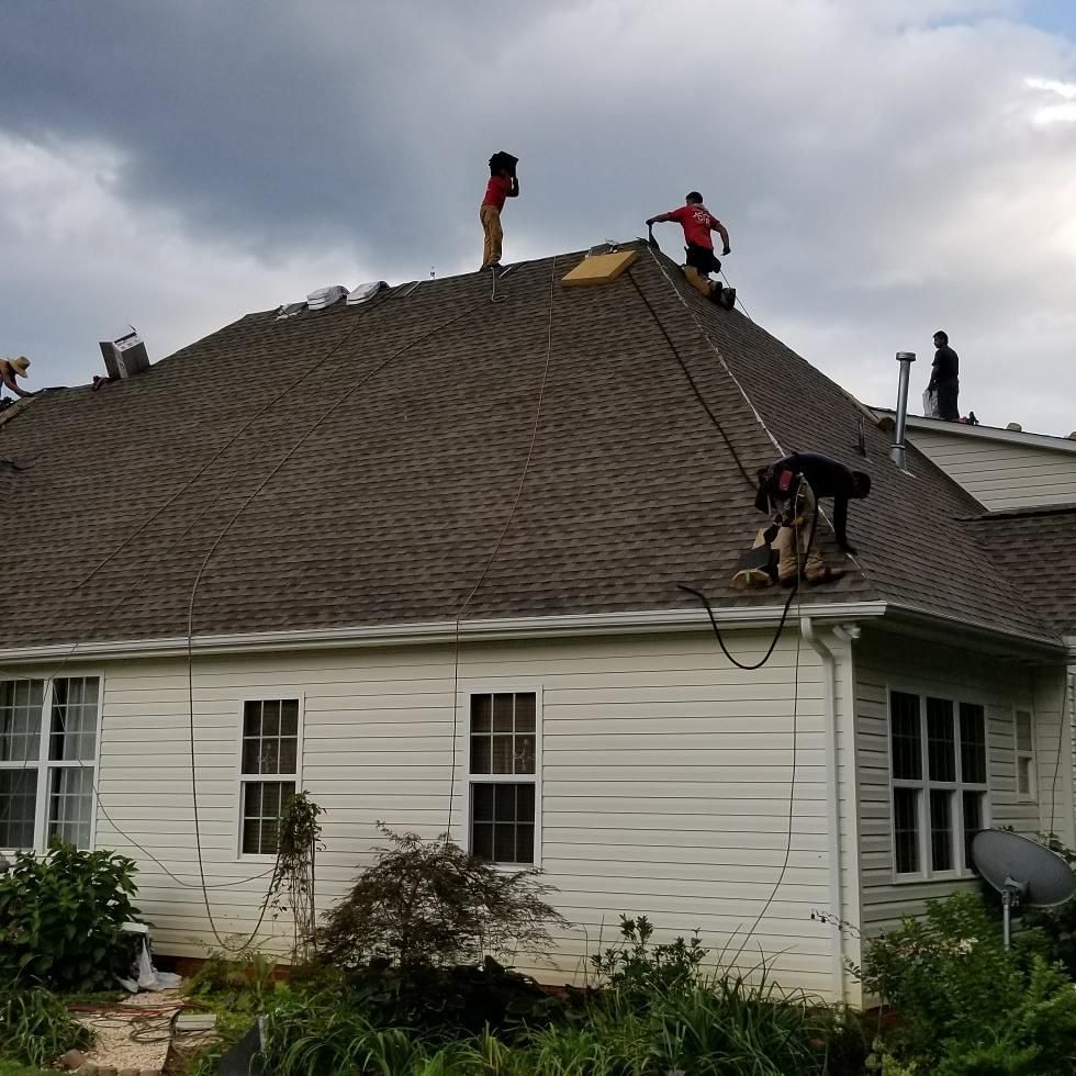 A group of men are working on the roof of a house