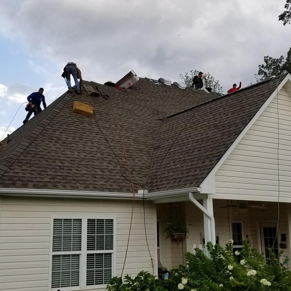 A group of people are working on the roof of a house.