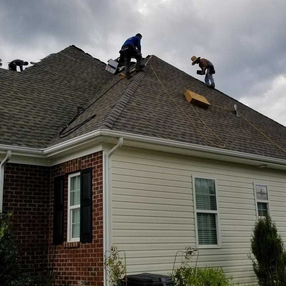 Two men are working on the roof of a house