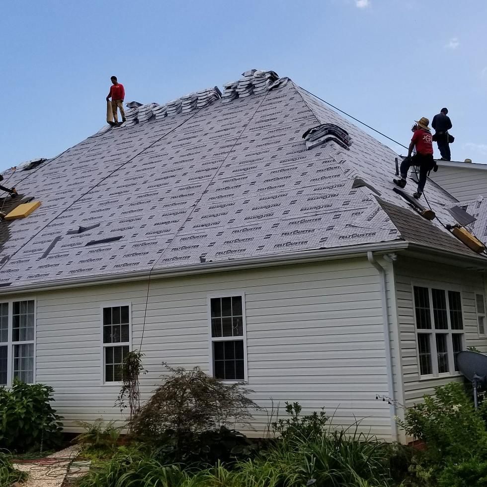 A group of people are working on the roof of a house