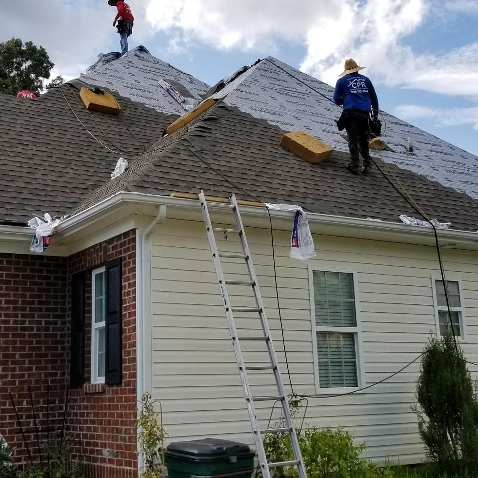 Two men are working on the roof of a house.