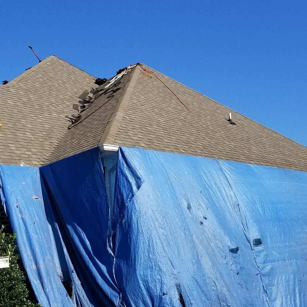 A blue tarp is covering the roof of a house