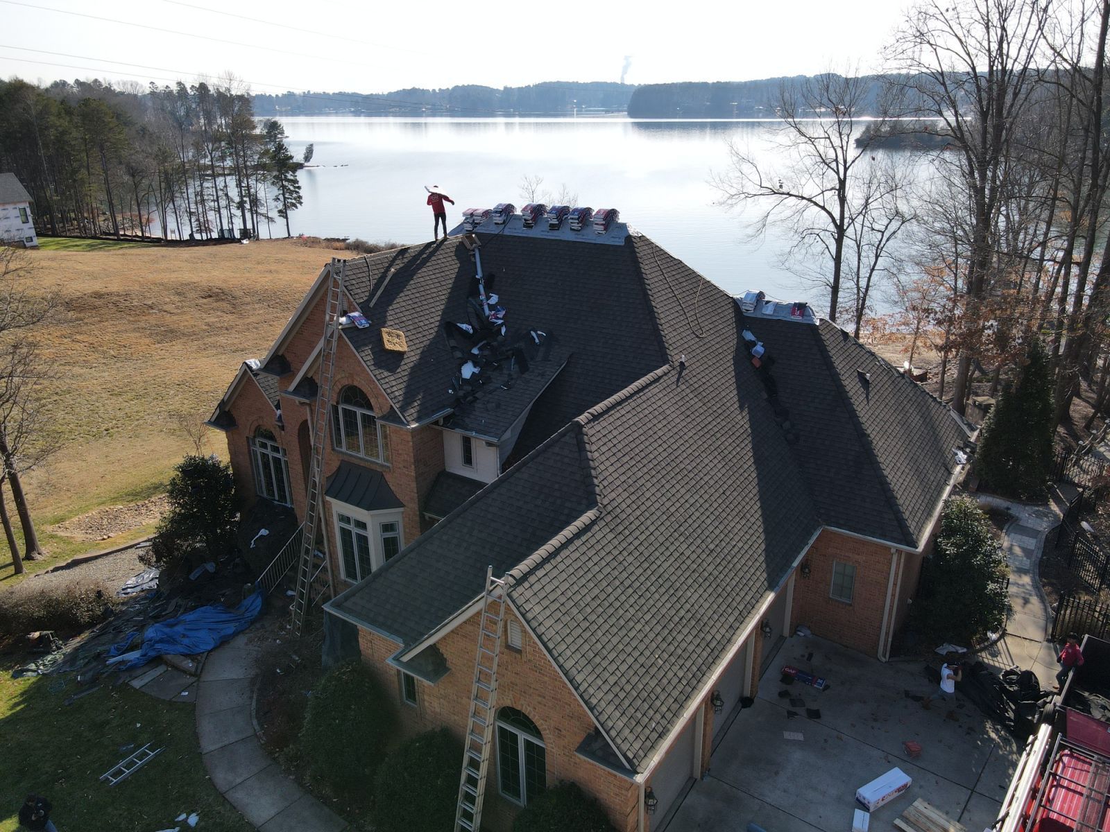 An aerial view of a large house with a lake in the background.