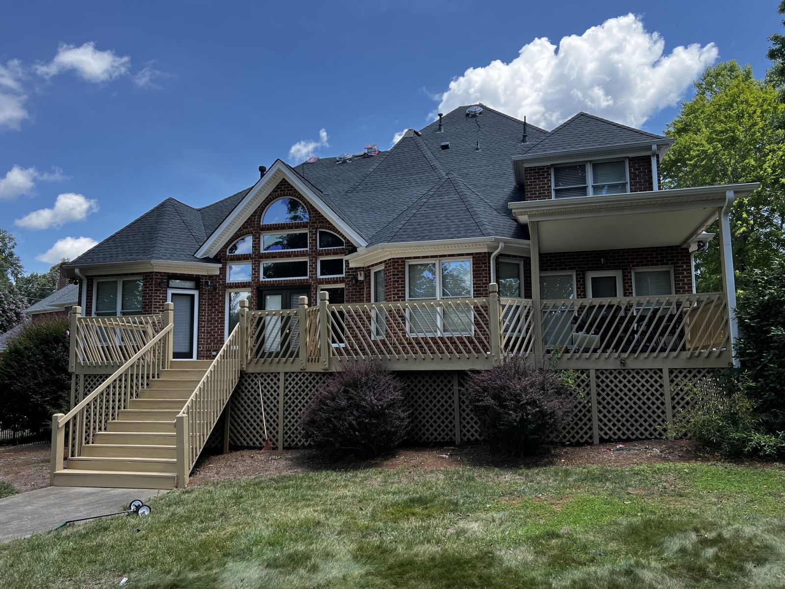 A large brick house with a large deck and stairs leading up to it.