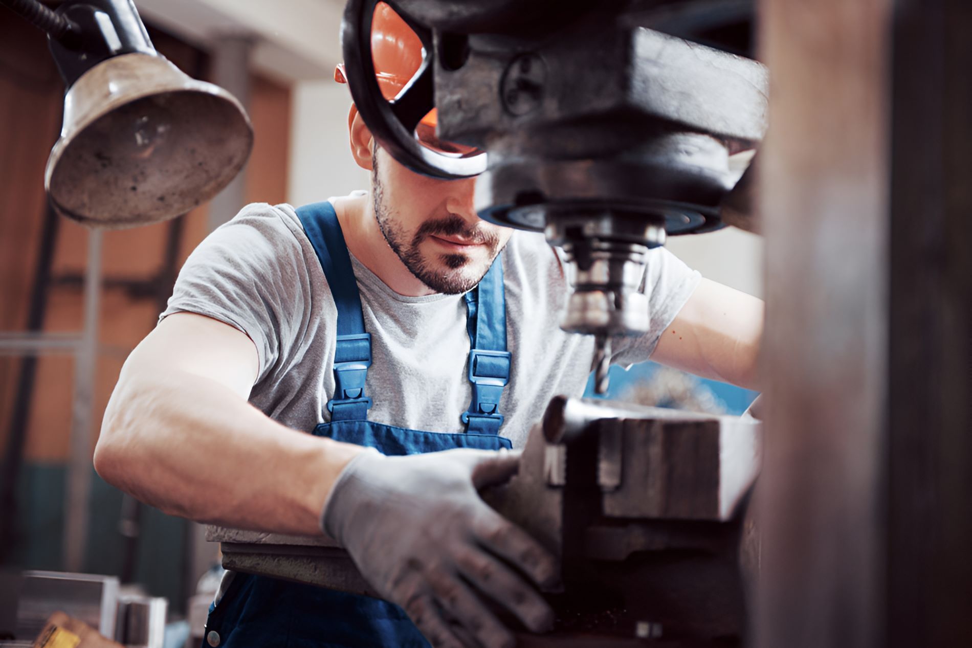A Man Is Working On A Machine In A Factory — Sunshine Coast Farrier Services In Landsborough, QLD