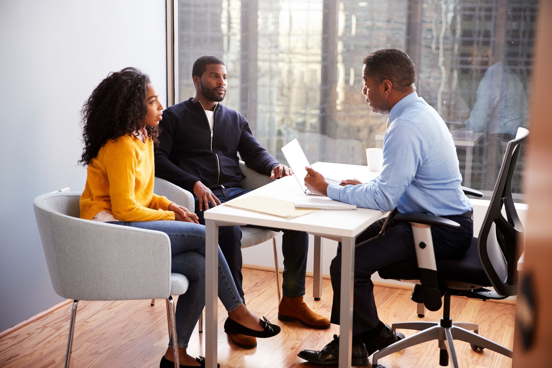 A man in a suit and tie is sitting at a table talking to a woman
