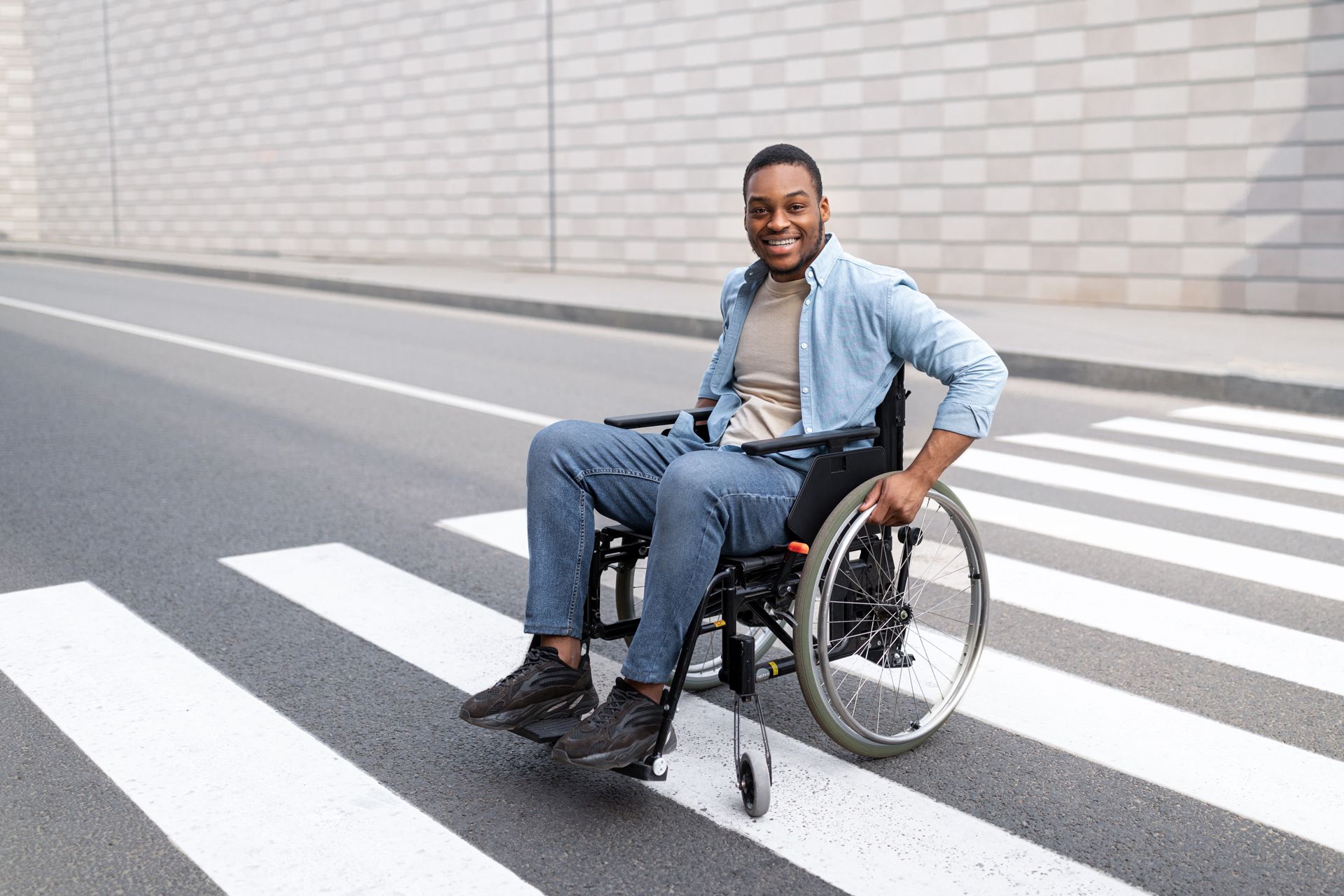 A man in a wheelchair is crossing a street