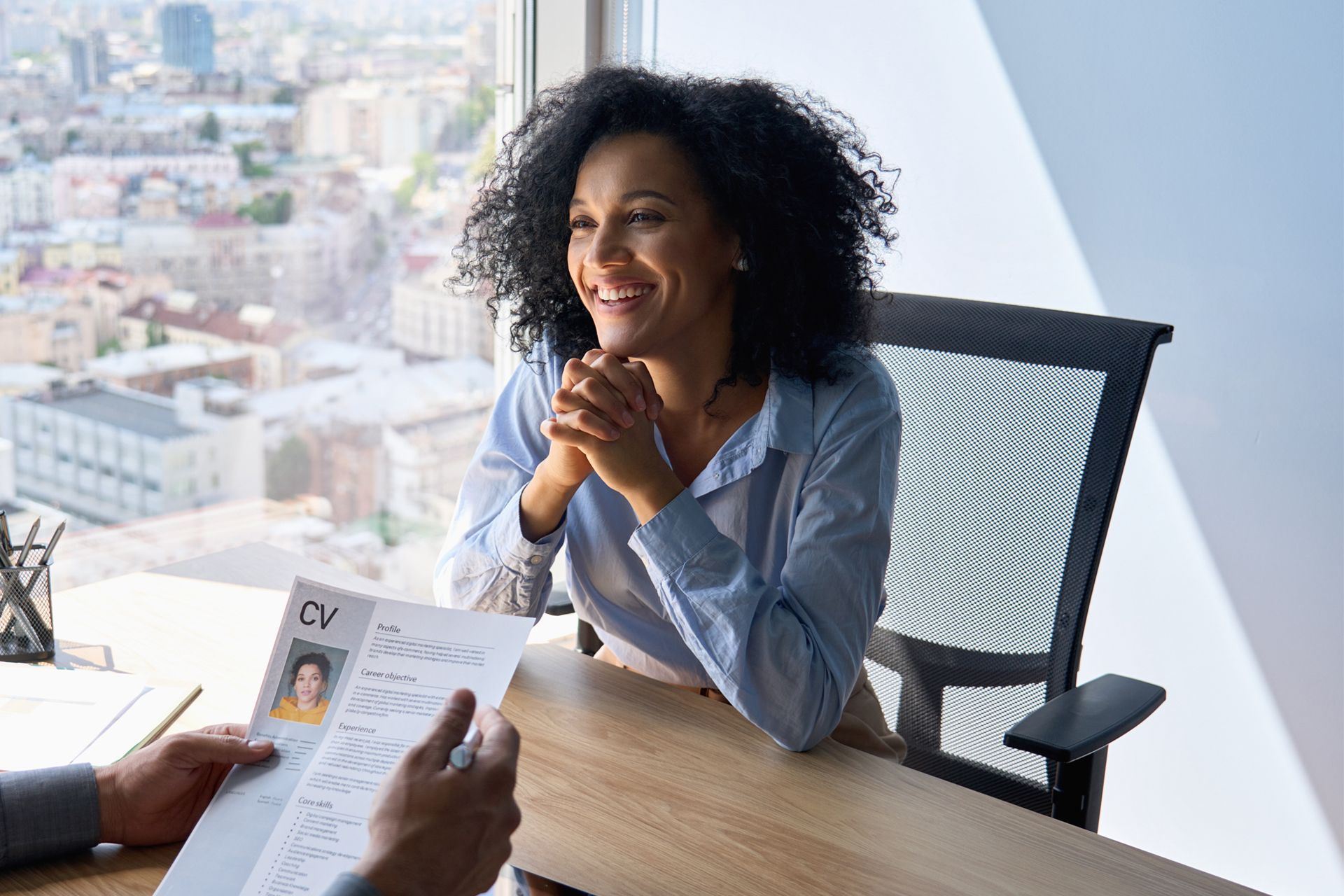 A woman is sitting at a desk talking to a man while holding a resume