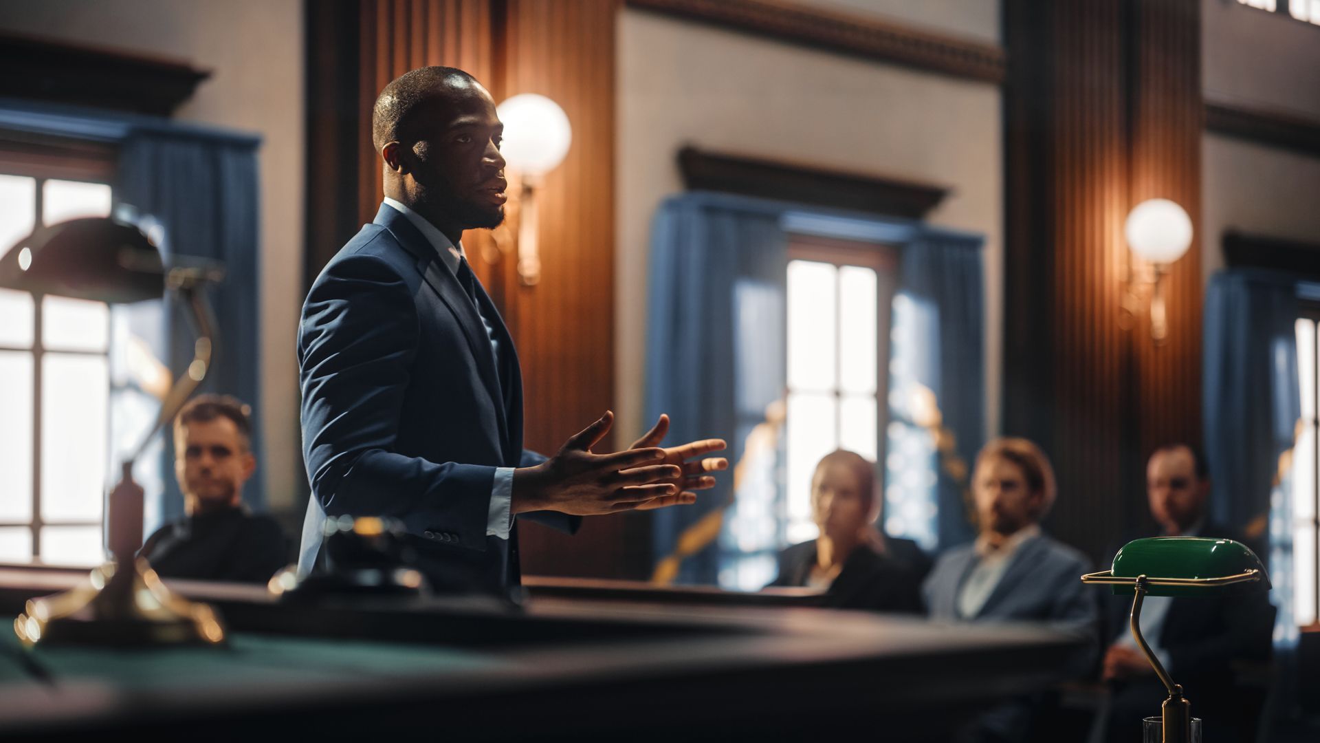 A man in a suit is giving a speech in front of a group of people in a courtroom