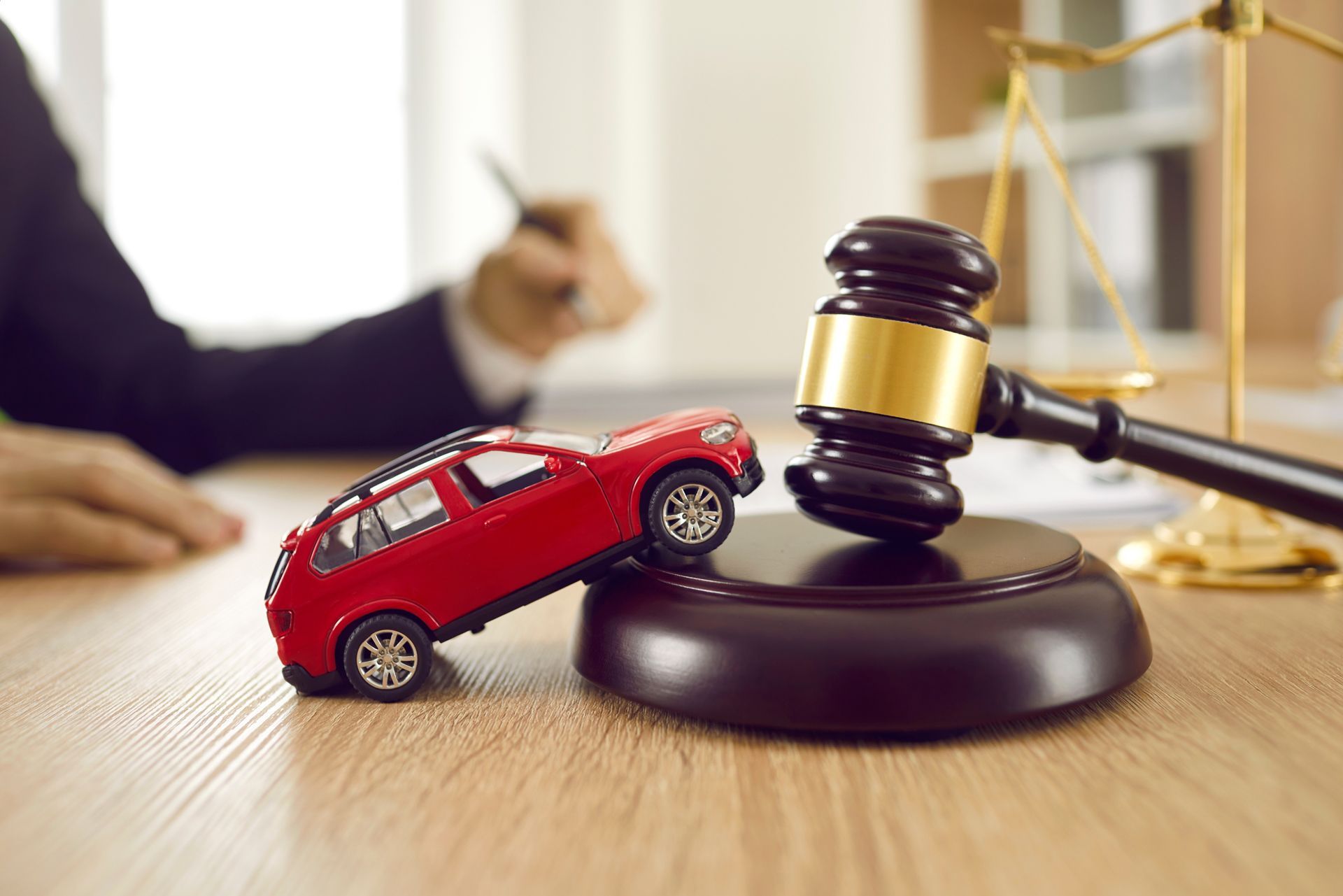 A toy car is sitting next to a judge 's gavel on a wooden table