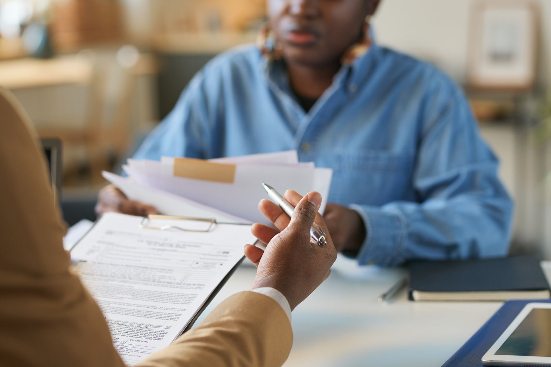 A man is sitting at a table holding a pen and a clipboard
