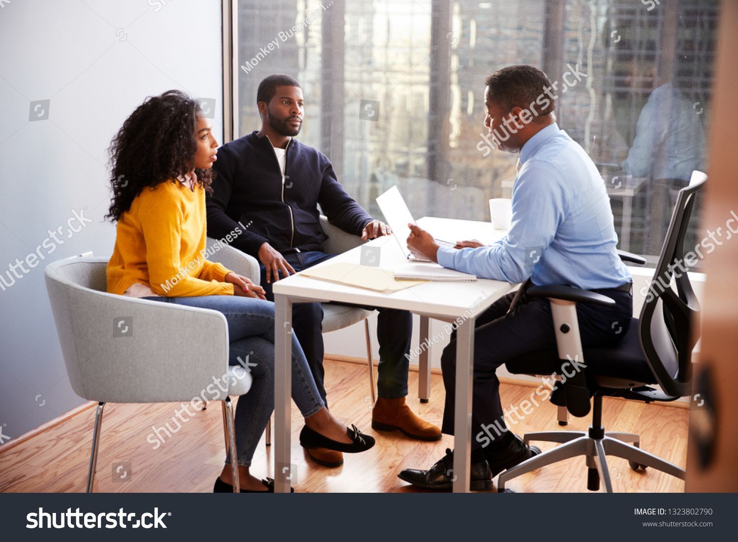 A man in a suit and tie is sitting at a table talking to a woman