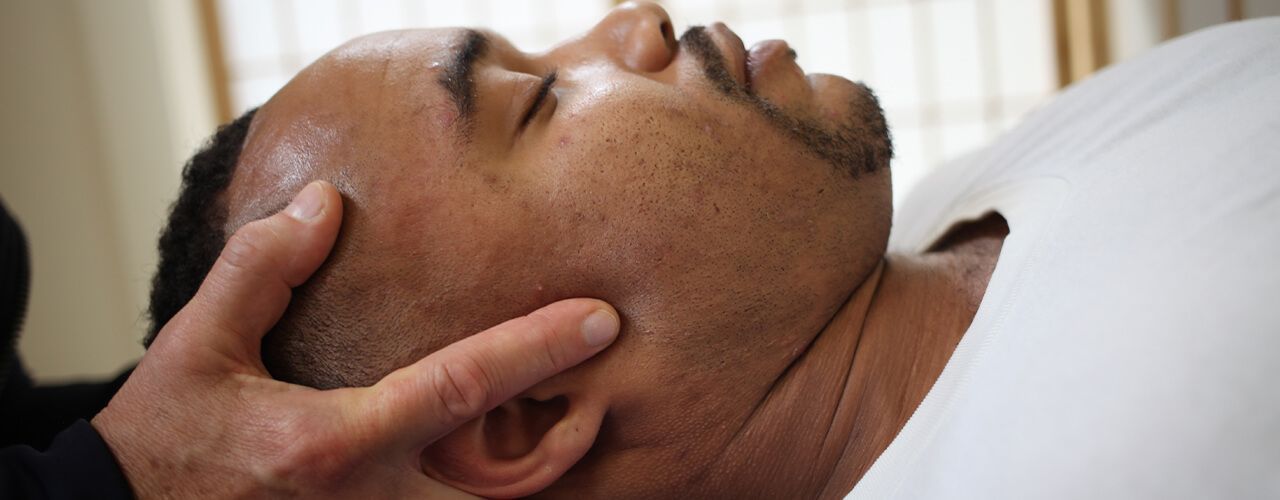 Woman receiving a back massage in a spa, with essential oil bottles and candles.