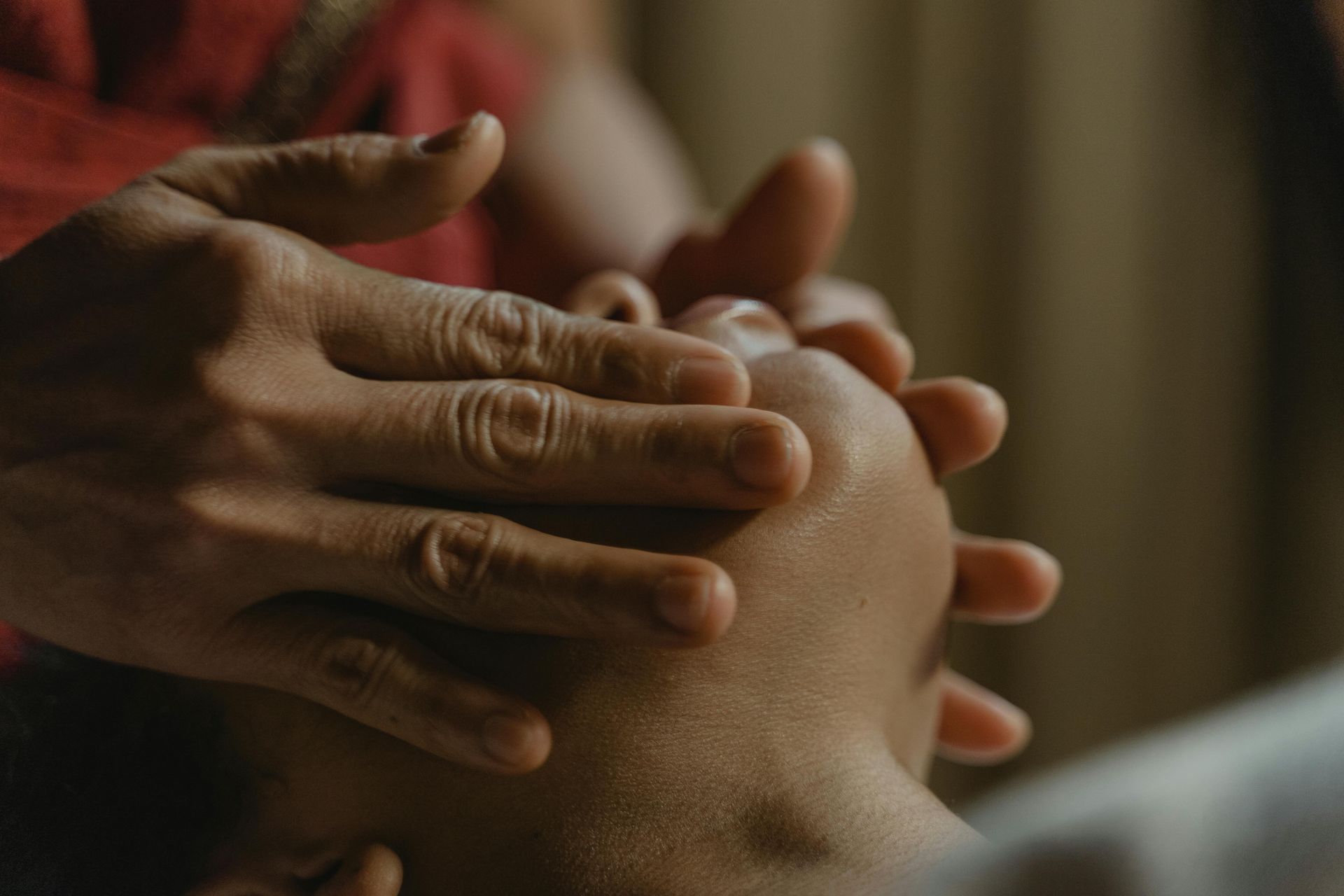 Woman receiving facial mask treatment at spa; hands applying mask, candles in background.