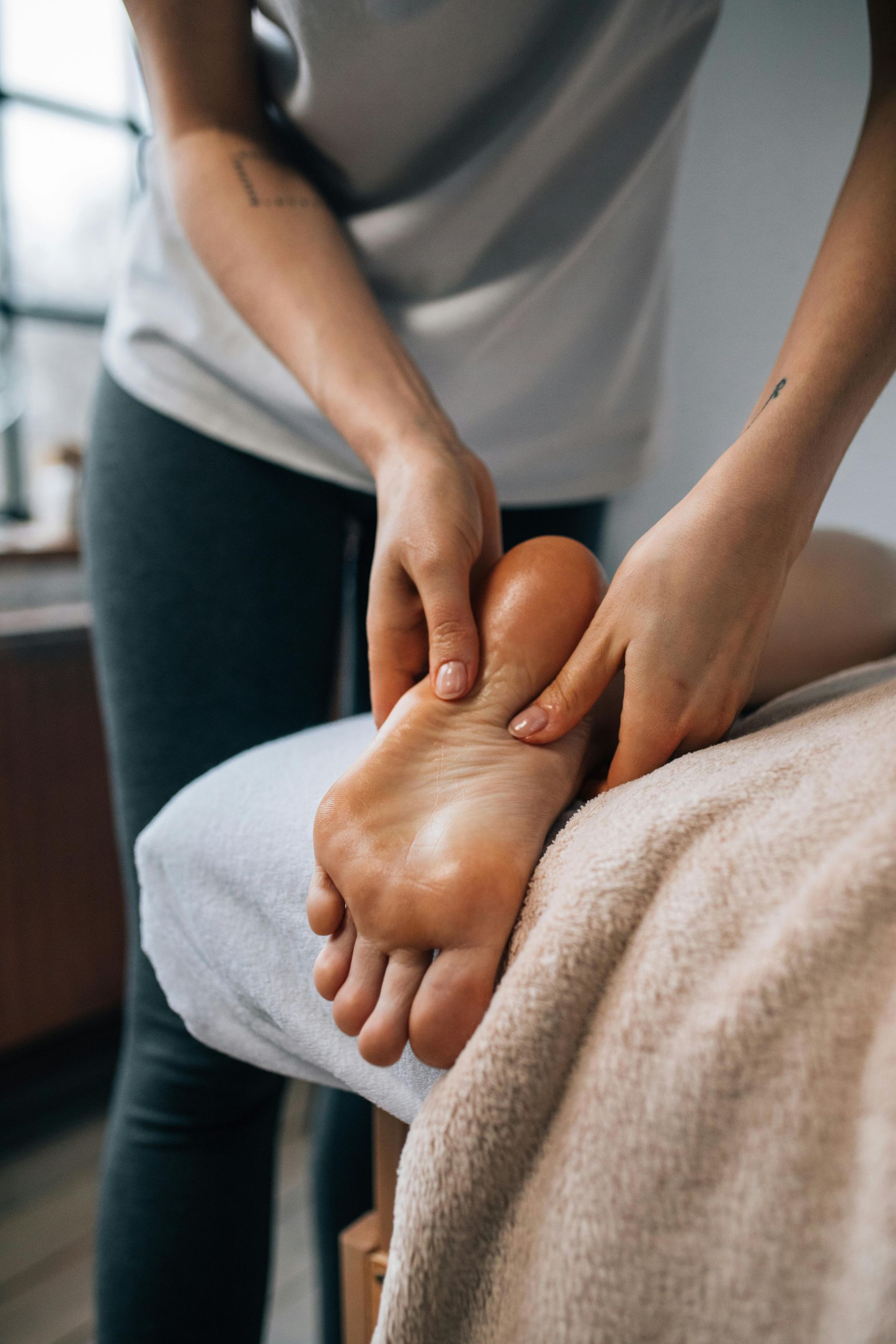 Person receiving a foot massage on a massage table indoors.