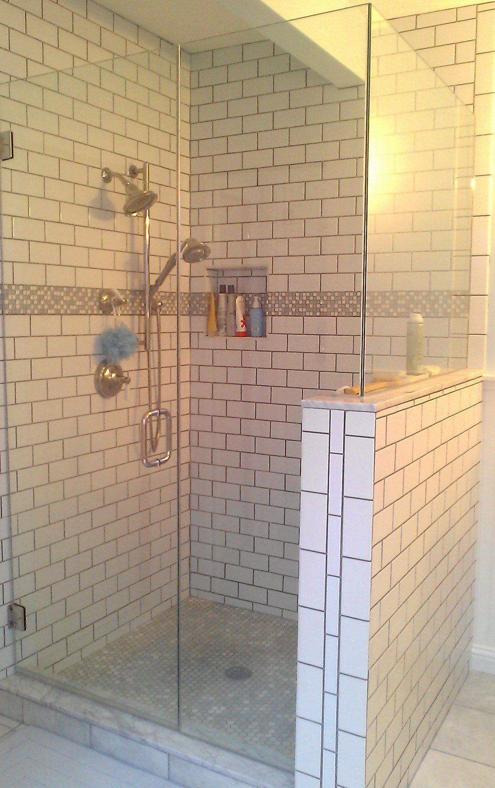Shower with white subway tiles, glass enclosure, and silver shower fixtures.