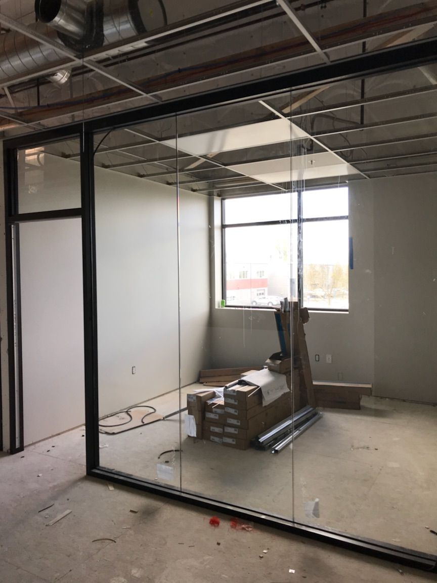 Office space under construction, with glass walls, window, and supplies.