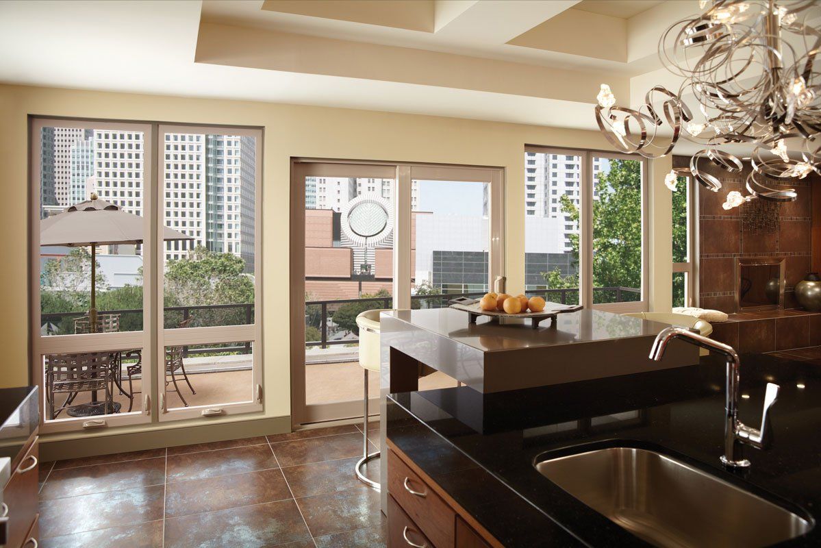 Kitchen with dark countertops, sink, and island; windows overlooking a city and a balcony.