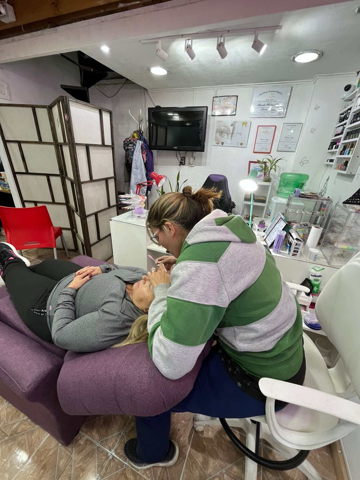 Una persona con un suéter a rayas se inclina sobre un cliente recostado en una sala de la clínica