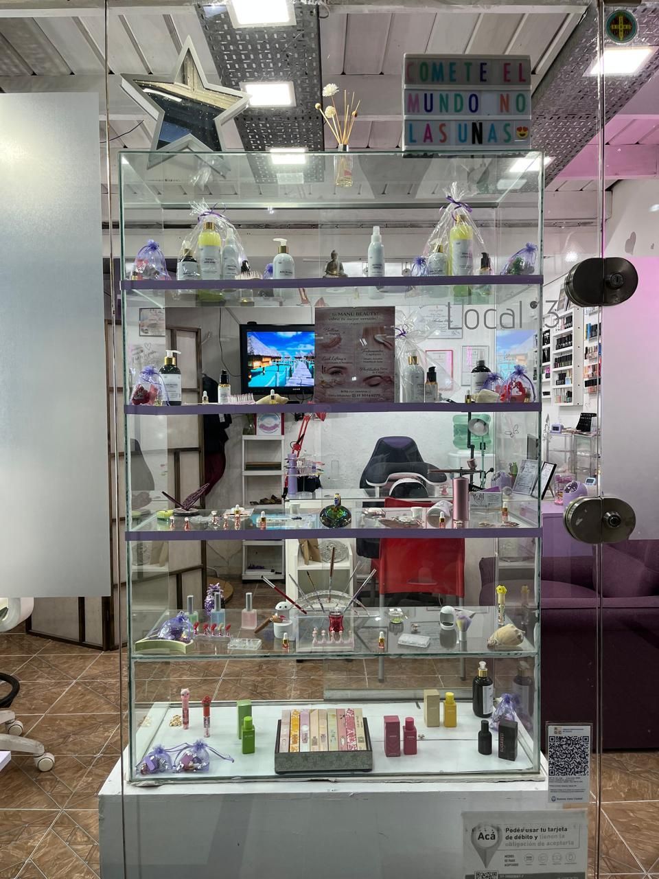 Vitrina de cristal con pequeños objetos decorativos y letreros en el interior de una tienda.