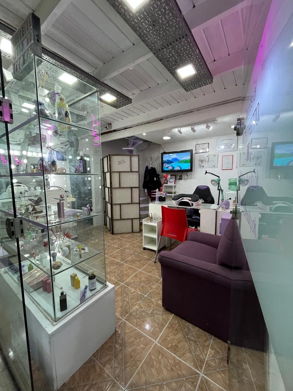 Interior de una pequeña tienda moderna con vitrinas de cristal, una silla roja, un sofá morado