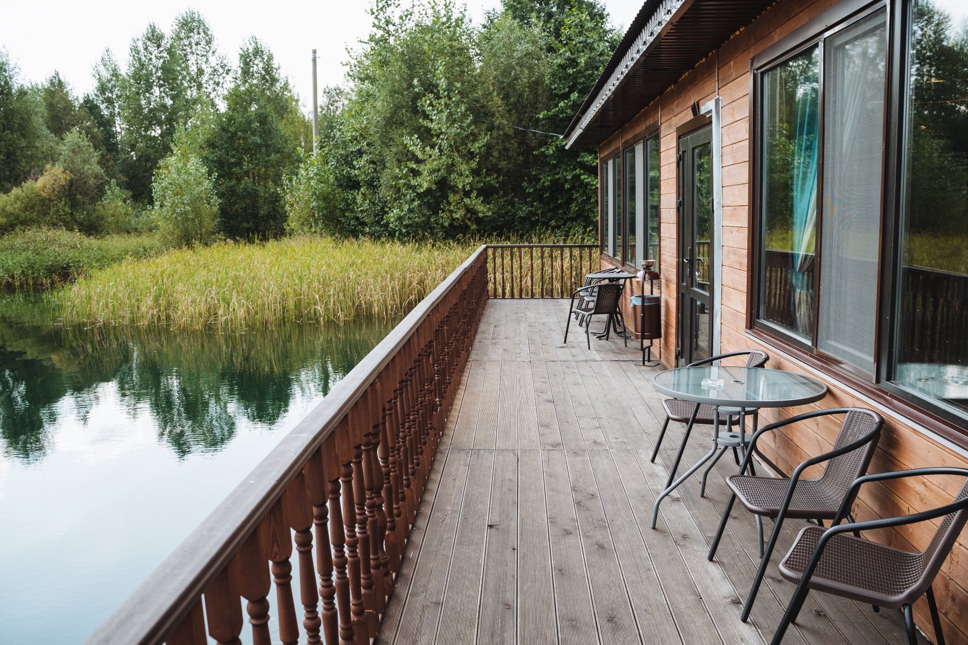 A wooden deck with chairs and tables overlooking a lake.