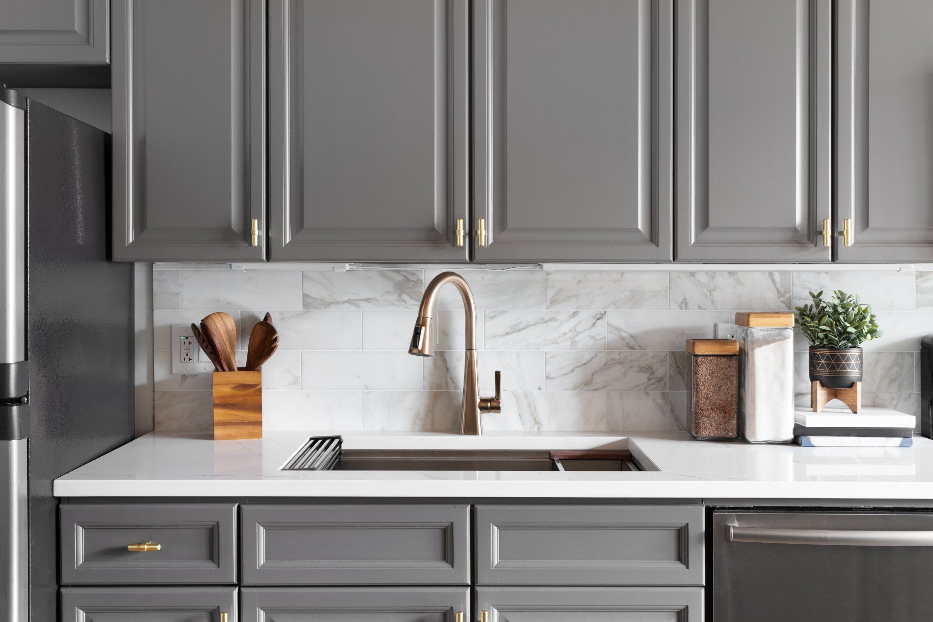 A kitchen with gray cabinets , a sink , a refrigerator , and a dishwasher.