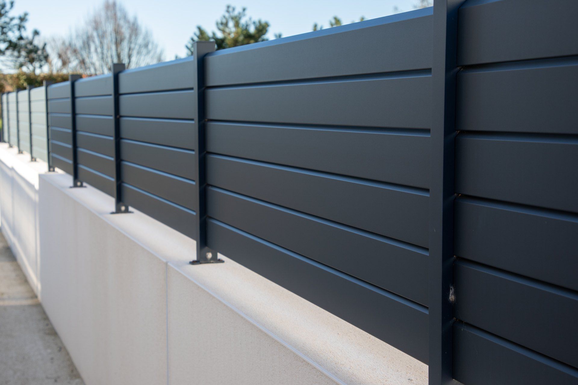 A black fence is sitting on top of a white wall.