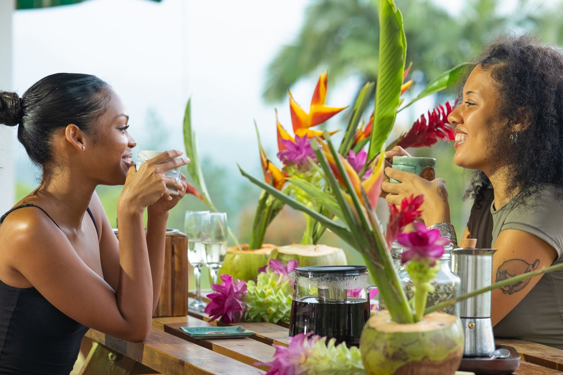 Two women are sitting at a table drinking from glasses.