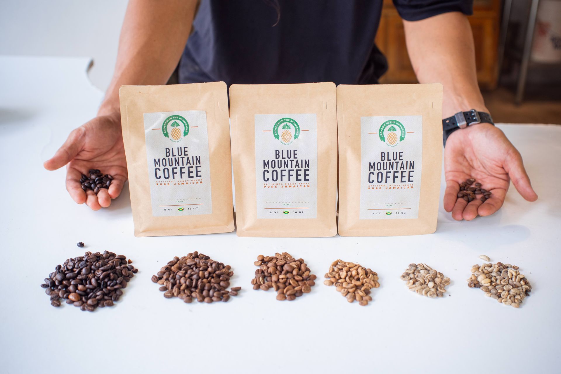 A man is holding three bags of coffee beans in his hands.