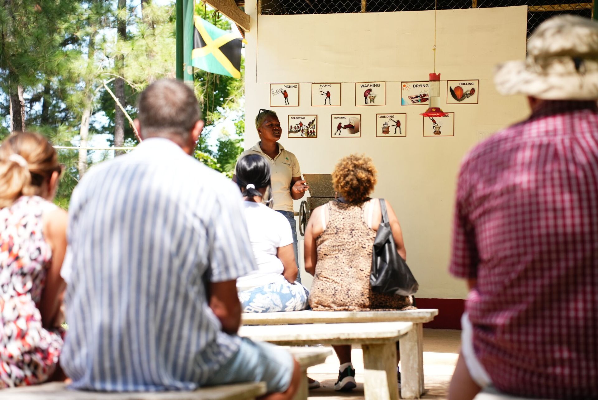 People sit on benches listening to an instructor talk about coffee production