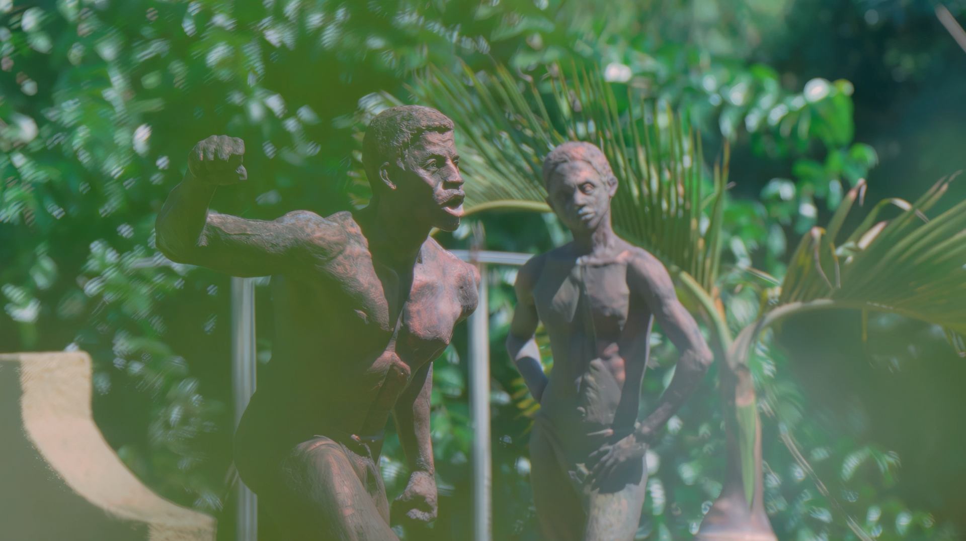 A couple of statues standing next to each other in a garden.