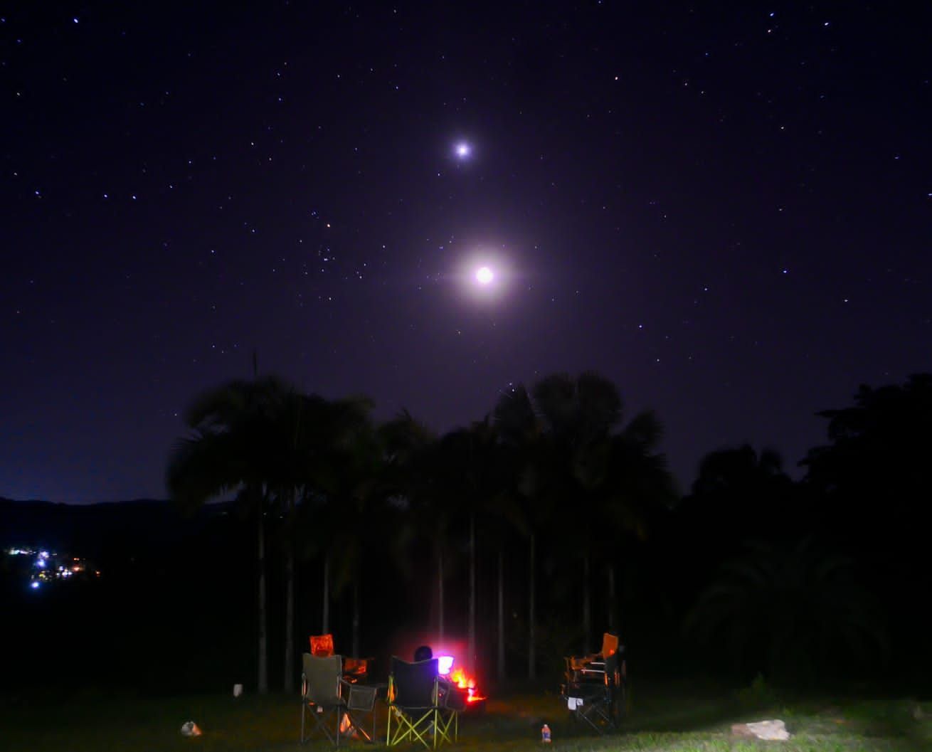 stars shine brightly above people sitting in camp chairs