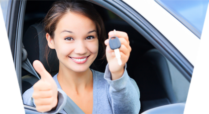 Girl with thumb up and key in her hand leaning out of a car window