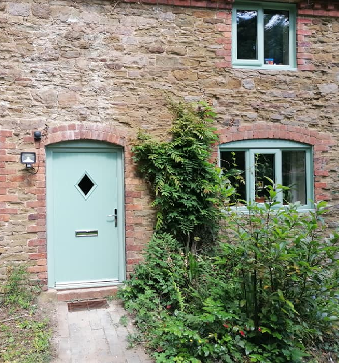 a brick building with a green door and two windows .