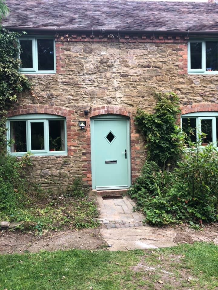 the front of a brick house with a blue door and windows .